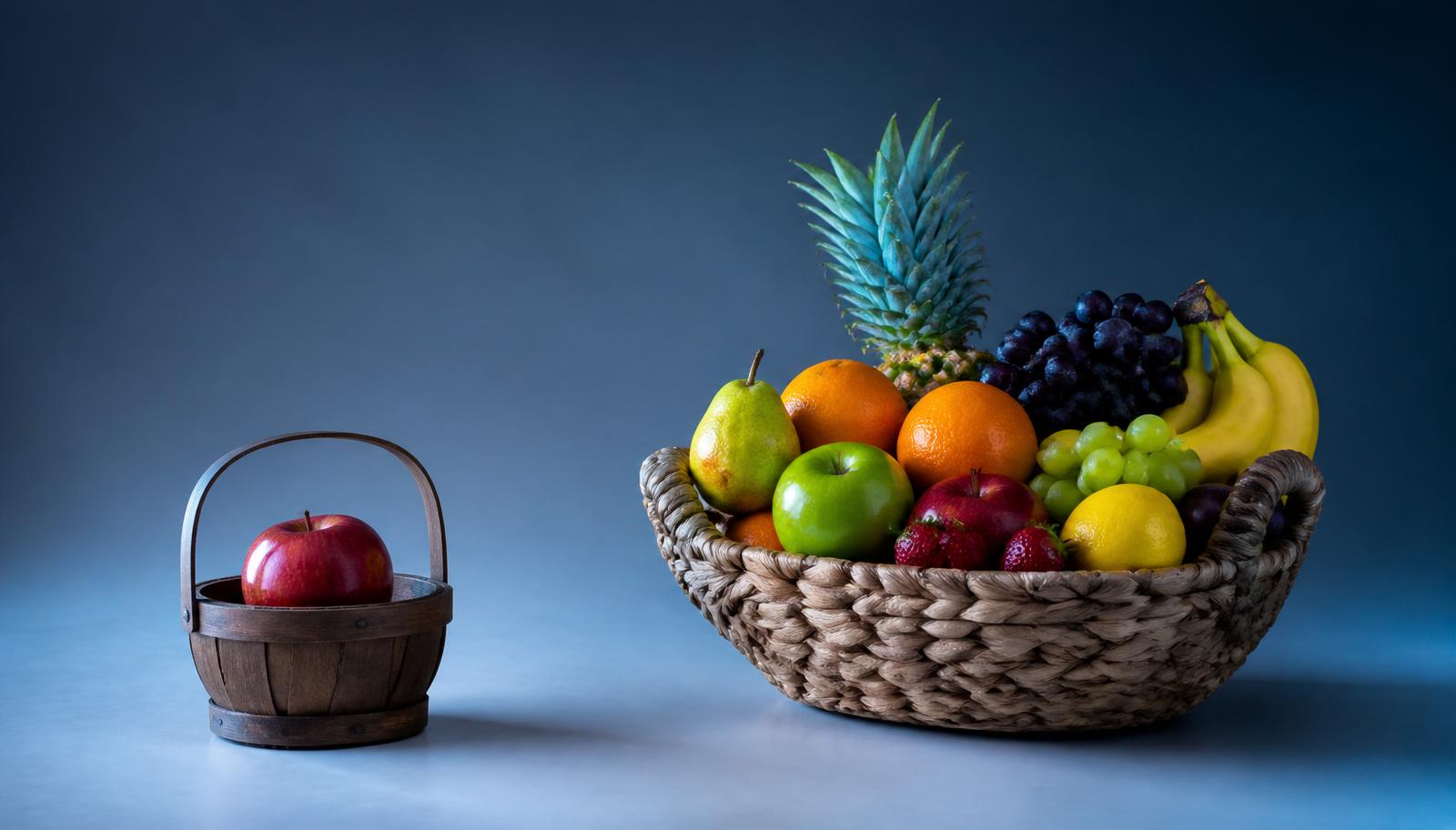 Kleiner Korb mit einem einzelnen Apfel neben einem grossen Korb mit vielen verschiedenen Früchten